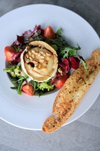 A delicious gourmet salad with grilled camembert, pine nuts, and toast.