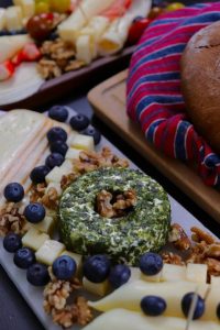 A vibrant cheese platter featuring various cheeses, fresh berries, nuts, and bread for a perfect brunch.