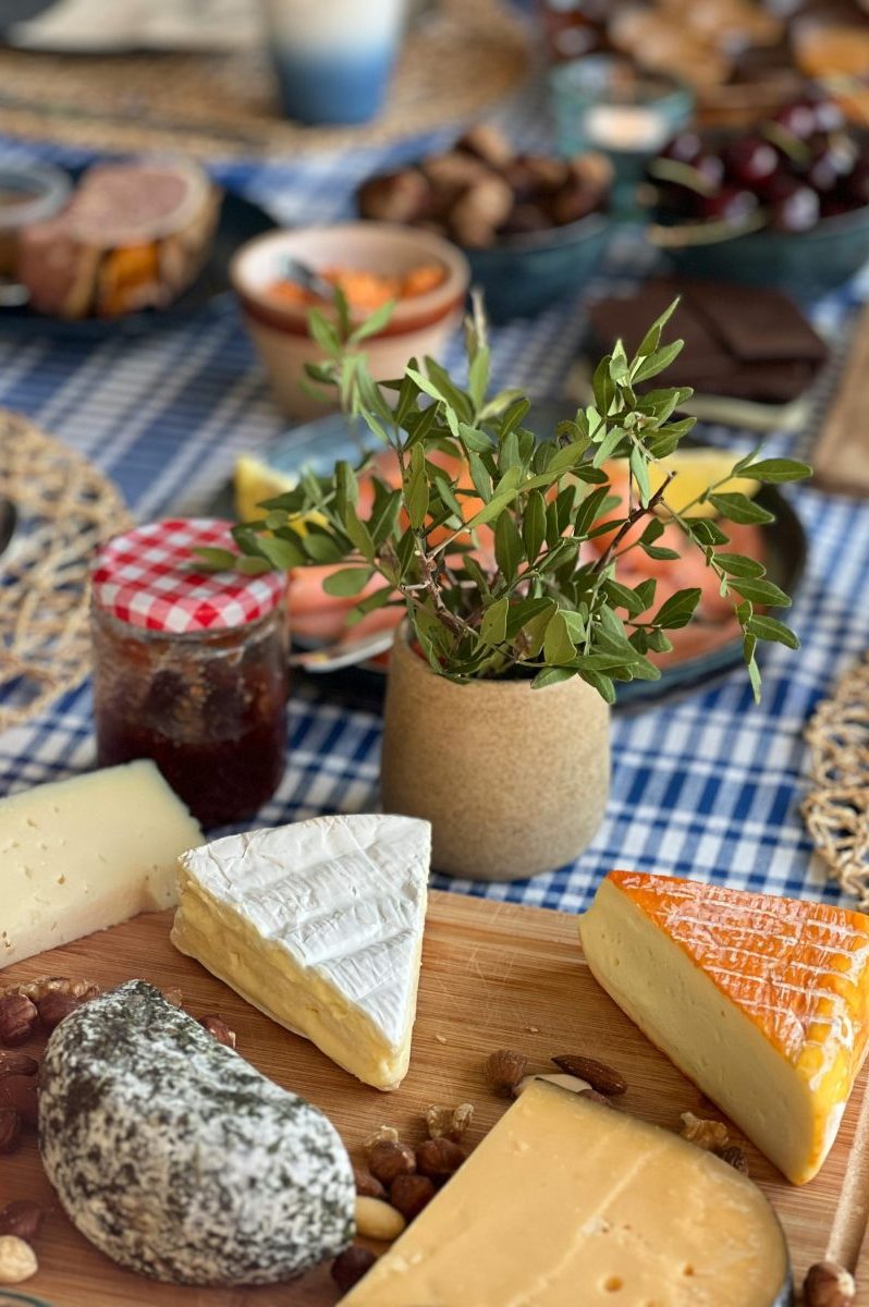 A rustic breakfast table spread with assorted cheeses, jam, and nuts, perfect for a cozy brunch setting.