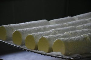 Rows of fresh goat cheese logs on a drying rack in a cheese factory. Perfect for culinary and artisanal themes.