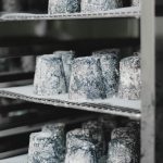 Rows of aged cheese on metal shelves in a dairy facility, highlighting traditional cheese-making processes.