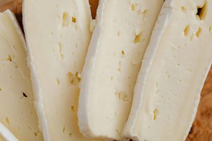 Close-up view of creamy cheese slices with a bloomy rind, perfect for culinary displays.