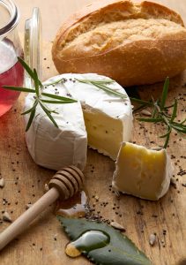 Cheese, bread, and honey on a wooden board.